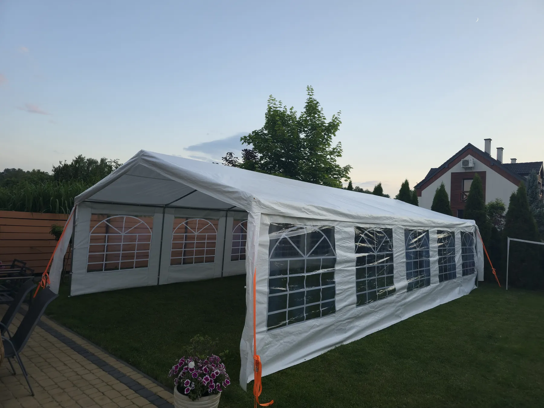 Namiot eventowy ustawiony w ogrodzie o zmierzchu
